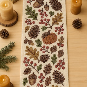 Puede incluir: Camino de mesa rectangular beige con motivos otoñales bordados. Presenta bellotas, piñas, hojas, bayas y una calabaza en tonos marrones, verdes y rojos. Ideal para la decoración de otoño, mide unos 30 cm de ancho.