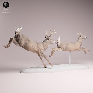 Pode incluir: Um conjunto de figuras em miniatura apresentando um veado castanho-claro com galhadas e uma corça numa pose de salto dinâmica. Ambos os animais estão capturados em movimento no ar, montados numa base branca alongada. O veado está à esquerda, enquanto a corça é apoiada por um pequeno poste branco no lado direito da base.