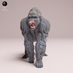 Op de afbeelding: Gedetailleerd beeldje van een gorilla in een dynamische pose, met zijn mond open, waardoor tanden zichtbaar zijn. De gorilla is voornamelijk grijs met lichtere vachtdetails. Het beeldje heeft een realistische uitstraling, met zichtbare spierdefinitie. Het logo "Animal Des Miniatures" staat linksboven.