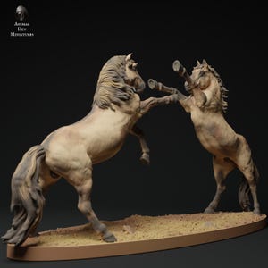 May include: A detailed sculpture of two horses rearing up, appearing to be in a fight. The horses are tan and brown, with detailed manes and tails. The sculpture is on a tan base with the text "Animal Den Miniatures".