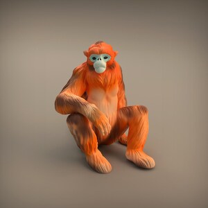 Op de afbeelding: Gedetailleerd beeldje van een gouden stompneusaap in zittende positie. De aap heeft fel oranje vacht met donkerbruine accenten op zijn ledematen en rug. Zijn gezicht heeft een lichtblauw masker en een witte neus.