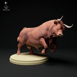 Può includere: Miniatura dettagliata di un toro in carica, di colore marrone-rossastro. Il toro ha corna bianche ricurve ed è posizionato su una base circolare color beige chiaro. Il testo "ANIMAL DEN MINIATURES" è visibile.
