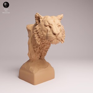 Può includere: Un busto di tigre monocromatico color marrone chiaro con una texture del pelo dettagliata, orecchie a punta ed un'espressione facciale concentrata. La testa della tigre è montata su una base rettangolare solida e finemente scolpita.