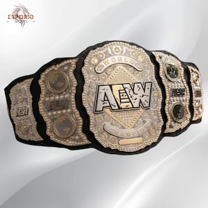 Può includere: Una cintura da campionato di wrestling professionale con un cinturino in pelle nera e intricate placche metalliche color argento. La placca centrale mostra il testo AEW WORLD CHAMPION con uno sfondo a forma di diamante. Le placche laterali hanno il logo AEW.
