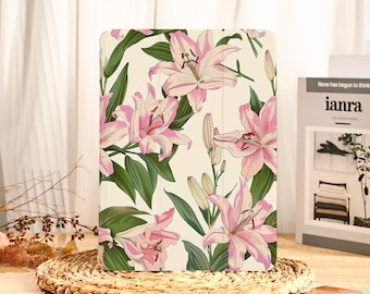 May include: An iPad case featuring a floral pattern of pink lilies and green leaves on a cream background. The case is rectangular and has a smooth finish. The design is a repeating pattern of the flowers and leaves.
