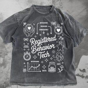 May include: Dark grey t-shirt with white graphics and text. The shirt features the words "Registered Behavior Tech" with related illustrations, including a brain, stopwatch, and data chart. The shirt has a vintage, washed appearance.