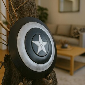 May include: A black, silver, and white shield with a central star design, mounted on a tree trunk. The shield has concentric circles in black and silver, with a white star in the center. The shield is a prop or decorative item.