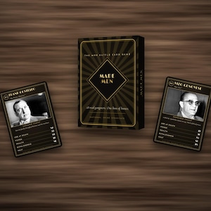 May include: A black and gold card game box titled Made Men with a sunburst design, accompanied by two playing cards featuring black and white portraits of Frank Costello and Vito Genovese, each displaying statistics for age, power, wealth, and heat.