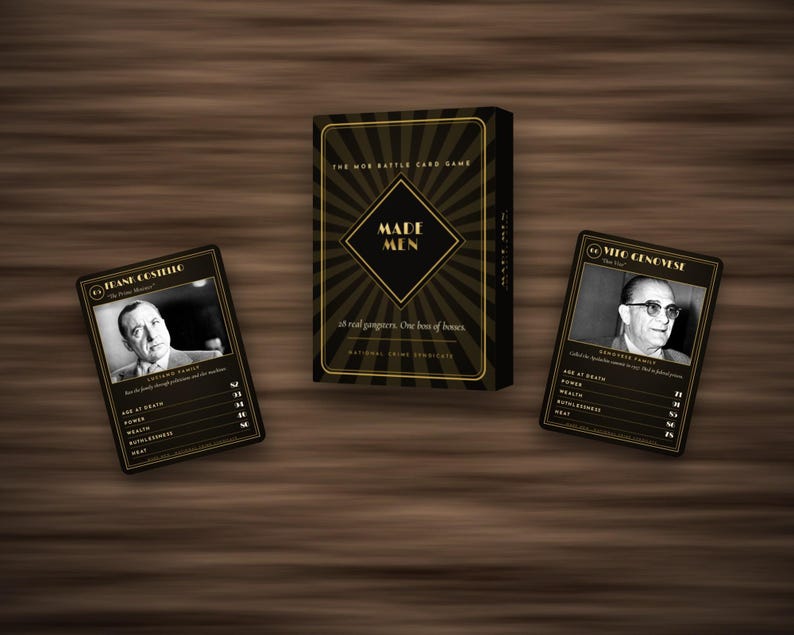 May include: A black and gold card game box titled Made Men with a sunburst design, accompanied by two playing cards featuring black and white portraits of Frank Costello and Vito Genovese, each displaying statistics for age, power, wealth, and heat.
