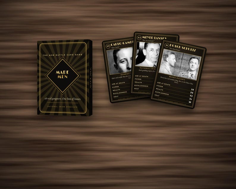 May include: A card game box titled Made Men with a black and gold sunburst design, accompanied by three playing cards featuring black and white portraits of historical figures including Carlo Gambino, Meyer Lansky, and Dutch Schultz with statistics.