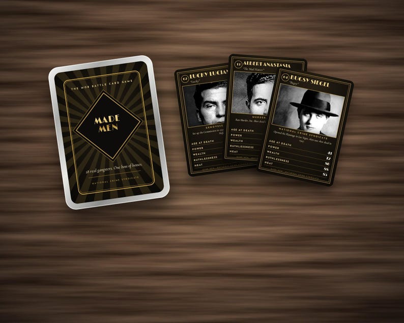 May include: A Made Men mob battle card game set featuring a black and gold deck box with sunburst patterns and three playing cards displaying black and white portraits of Lucky Luciano, Albert Anastasia, and Bugsy Siegel with statistical data.