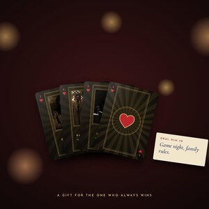 May include: Four playing cards with a dark, sunburst-patterned background and a red heart symbol. A small rectangular card displays the text: "DEAL HIM IN Game night, family rules." Below, the text reads: "A GIFT FOR THE ONE WHO ALWAYS WINS."