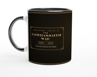May include: A black ceramic mug with a gold-colored rectangular border containing the text: MOB HISTORY - FACT No. 03 THE CASTELLAMMARESE WAR 1930 - 1931 The war that made the Five Families. The mug features a white interior and a black handle.