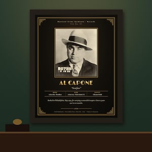 May include: A framed black and gold poster featuring a vintage mugshot of Al Capone wearing a fedora and suit. The text includes his name, nickname Scarface, birth and death dates, and biographical details from the National Crime Syndicate Records.