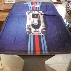 May include: A rectangular blue mat with a race car design. The mat features a white race car with the number 22, and the text "24 HEURES DU MANS". The design includes red, white, and blue stripes.