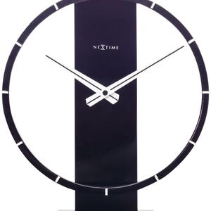 Op de afbeelding: Een moderne zwarte bureauklok met een minimalistisch ontwerp. De klok heeft een cirkelvormig frame met witte markeringen, witte wijzers en een zwarte rechthoekige basis. De merknaam "NEXTIME" staat op de wijzerplaat.