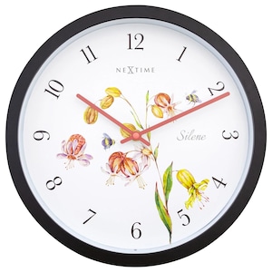 Könnte beinhalten: Runde Wanduhr mit schwarzem Rahmen und weißem Zifferblatt. Das Zifferblatt zeigt ein Blumendesign mit gelben, orangefarbenen und lila Blumen, und die Zeiger sind lachsfarben. Die Uhr trägt die Aufschriften "NEXTIME" und "Silene".