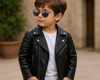 Peut inclure: Une veste de moto en cuir noir avec des fermetures éclair et des boutons-pression argentés, portée sur un t-shirt blanc uni. La veste présente des détails matelassés aux épaules et un large col à revers. Tenue avec jean foncé et lunettes rondes.