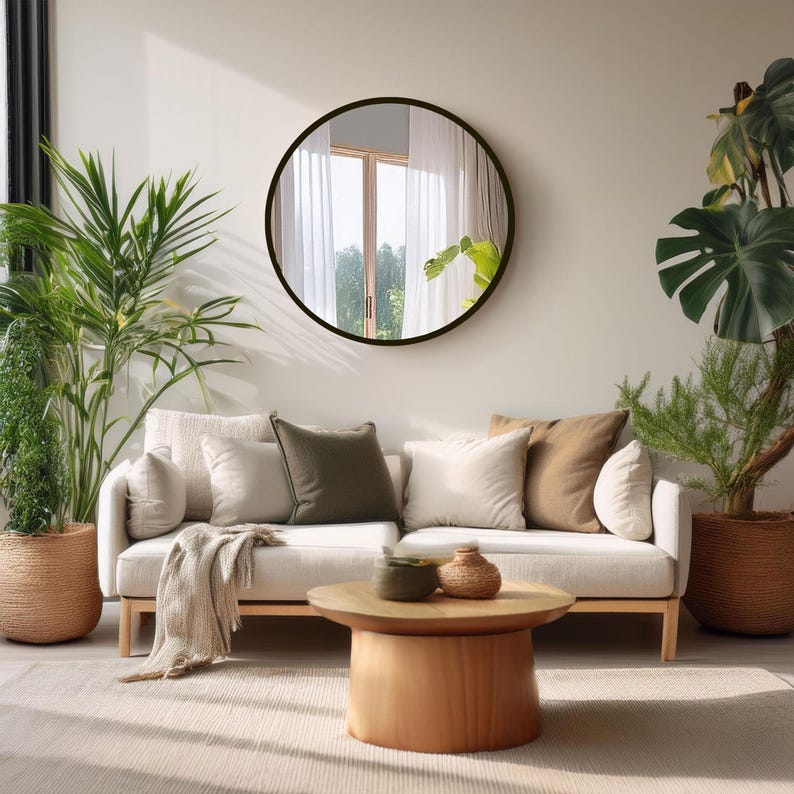 A living room scene featuring a light-colored sofa with several pillows, and a large round mirror.