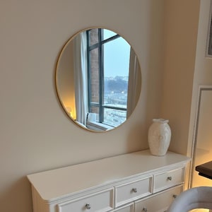 round mirror with gold frame on the dresser.