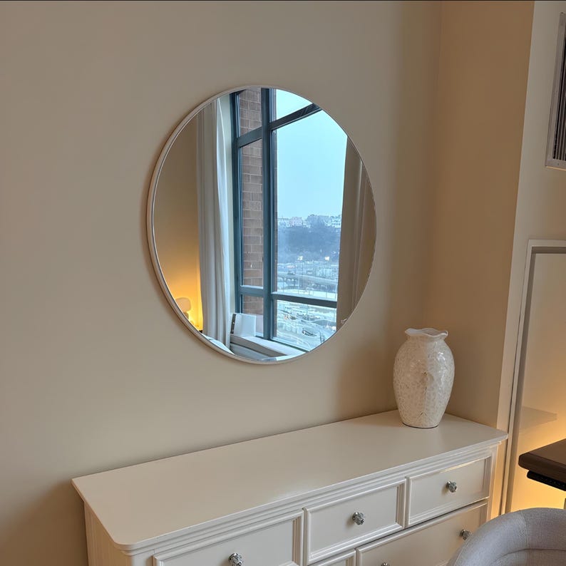 round mirror with white frame on the dresser.