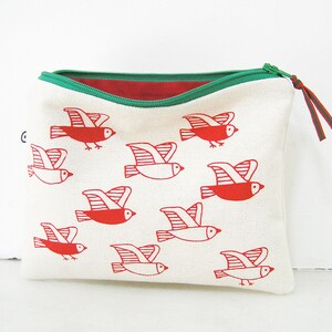 May include: A white canvas zippered pouch with a red and green zipper and a red and white bird print. The birds are stylized and have a simple design.
