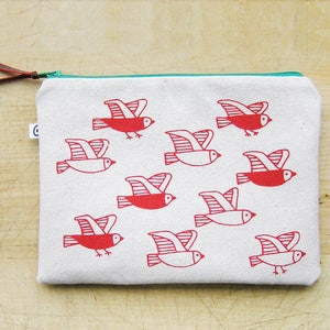 May include: A white canvas zippered pouch with a red and white bird design. The birds are flying in different directions. The zipper is teal.