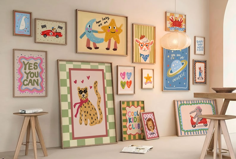 May include: A collection of framed art prints with whimsical illustrations. The prints feature a variety of themes, including a cheetah with sunglasses, a car, a moon and star, and the text "YES YOU CAN". The color palette includes pink, green, and yellow.