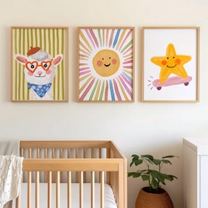 May include: Three framed art prints featuring whimsical illustrations. One shows a llama wearing heart-shaped glasses and a beret, another a smiling sun with colorful rays, and the last a star riding a skateboard. The prints are in wooden frames.