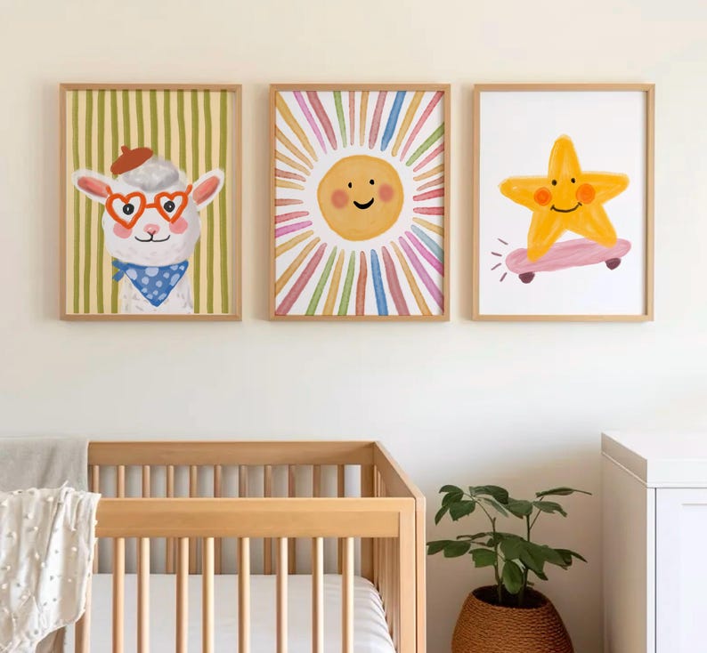May include: Three framed art prints featuring whimsical illustrations. One shows a llama wearing heart-shaped glasses and a beret, another a smiling sun with colorful rays, and the last a star riding a skateboard. The prints are in wooden frames.