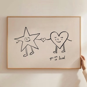 Peut inclure: Une affiche encadrée avec une illustration en noir et blanc d'une étoile et d'un cœur, chacun avec des bras et des jambes, se tenant la main. Le texte "you are so loved" est écrit en dessous.