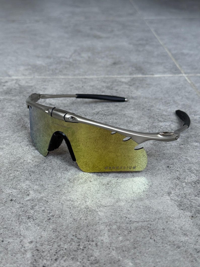 May include: Silver-framed sunglasses with a yellow-green gradient lens. The sunglasses have a sleek, modern design with black ear pieces. The lenses are a vibrant yellow-green color, and the frame is a metallic silver.