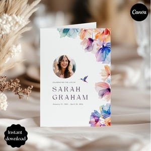 Può includere: Un biglietto commemorativo bianco con accenti floreali ad acquerello nei toni del blu, viola e arancione. Il biglietto presenta una foto di una donna, il testo "Celebrating the Life of Sarah Graham" e le date. Il logo Canva e il testo "Download istantaneo" sono visibili.