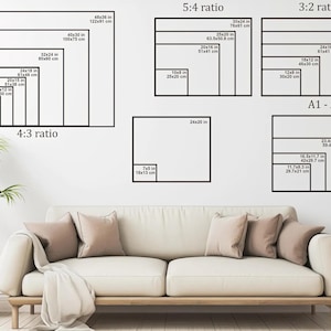 a living room with a white sofa and a potted plant. The sofa has a 4-3 ratio design, and the potted plant is placed next to the sofa. The wall behind the sofa has a series of framed images with different sizes and designs, including a 5-4 ratio, a 3-2 ratio, and a 4-3 ratio.