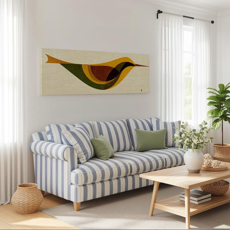 Op de afbeelding: Een woonkamer met een blauw-witte gestreepte bank en groene kussens. Boven de bank hangt een rechthoekig kunstwerk met een gestileerde vogel in geel, bruin en groen. Een houten salontafel en een plant in een pot zijn ook zichtbaar.