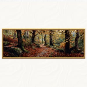 Könnte beinhalten: Gerahmtes Landschaftsgemälde einer herbstlichen Waldszene. Ein Pfad schlängelt sich durch Bäume mit goldenen und braunen Blättern, der Boden ist mit Laub bedeckt. Das Kunstwerk ist in einem goldfarbenen Rahmen präsentiert, der die natürliche Schönheit hervorhebt.