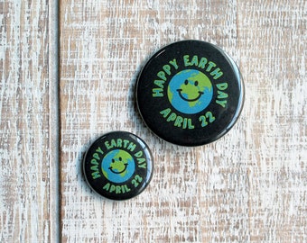May include: Two black button pins with a green and blue Earth graphic and the text "Happy Earth Day April 22".