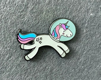 May include: A white unicorn wearing a blue astronaut helmet with pink and blue hair and a silver star on its side.