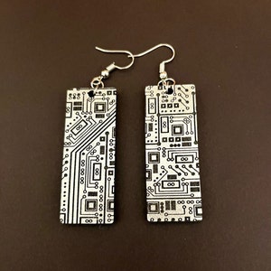 Op de afbeelding: Een paar zilveren oorbellen met een rechthoekig ontwerp met een zwart-wit circuitboardpatroon.