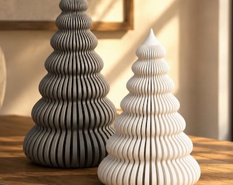 May include: Two conical sculptures shaped like stylized trees, one in a dark charcoal gray and the other in a crisp white. Each piece features a series of stacked, rounded horizontal ridges that create a ribbed, layered texture from base to tip.