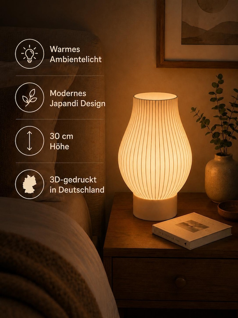 May include: A white table lamp with a ribbed, vase-shaped shade emitting a warm glow. The lamp stands on a cylindrical base. Text on the image indicates: Warmes Ambientelicht, Modernes Japandi Design, 30 cm H&ouml;he, 3D-gedruckt in Deutschland.