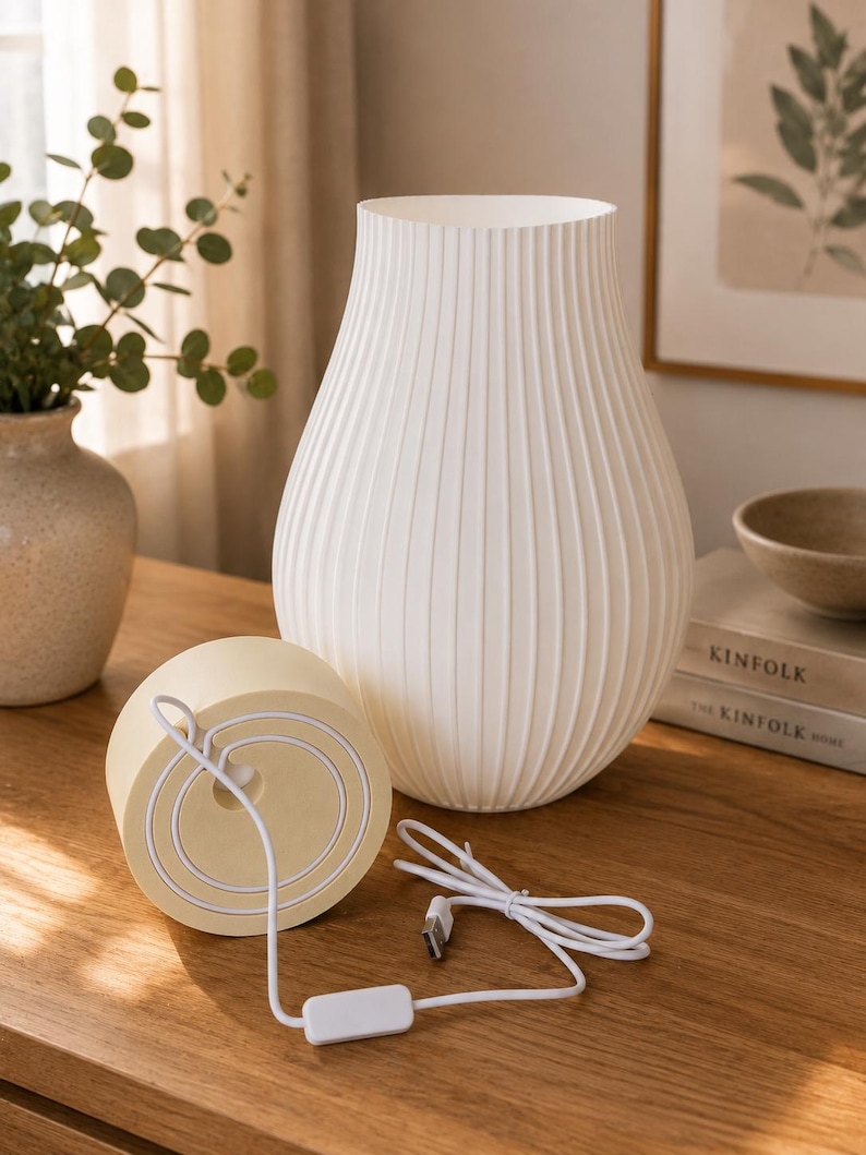 May include: A white, ribbed, vase-shaped table lamp with a rounded base. The lamp features a light-colored, circular wooden base component with a white power cord, a small rectangular inline switch, and a standard USB connector attached to it.