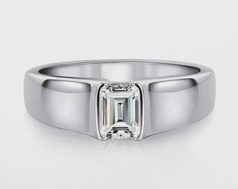 May include: A silver ring with a rectangular, emerald-cut gemstone set in the center. The band is thick and polished, with a smooth, reflective surface. The ring is displayed against a plain white background.