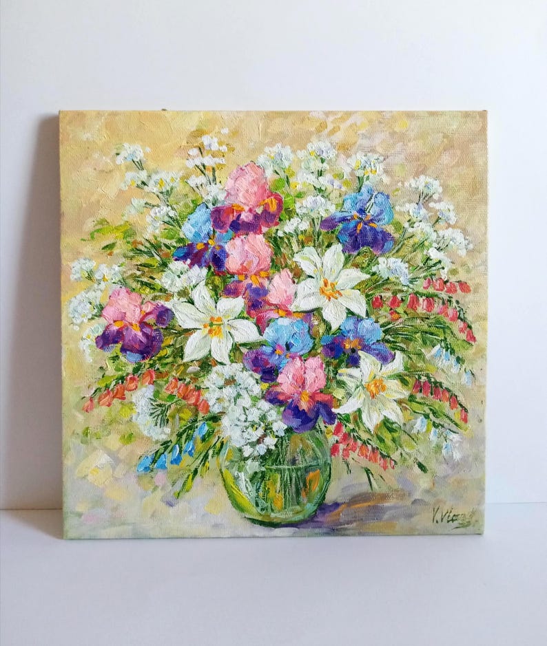 May include: An original oil painting of a floral arrangement in a clear glass vase. The bouquet features white lilies, pink, purple, and blue irises, and small white flowers. The background is a soft yellow with visible brushstrokes.