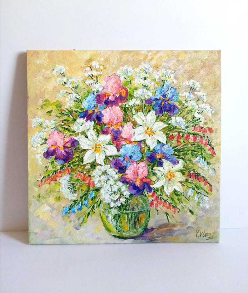 May include: Oil painting of a vibrant floral arrangement in a clear glass vase. The bouquet features irises in shades of purple, pink, and blue, along with white and red flowers. The background is a soft, yellow-toned canvas.
