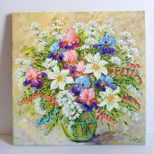 May include: Oil painting of a vibrant floral arrangement in a clear glass vase. The bouquet features irises in shades of pink, purple, and blue, along with white lilies and delicate white blossoms. The background is a soft, textured yellow.