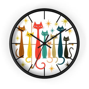 May include: A round wall clock with a black frame and a white face. The clock face features a colorful illustration of stylized cats in various colors, including brown, yellow, red, and teal. The clock hands are black.