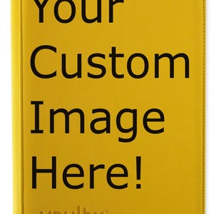 May include: A yellow binder with the text "Your Custom Image Here!" in large black letters. The brand name "vaultx" is embossed at the bottom. The binder has a zipper and a small tab.