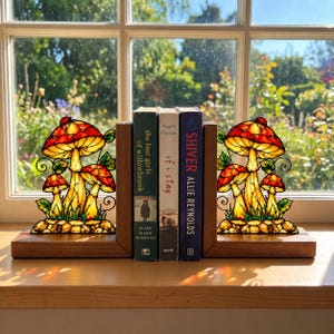 May include: A pair of wooden bookends featuring stained glass panels with red and yellow mushroom designs, green leaves, and black metal outlines. The bookends hold three books titled The Lost Girls of Willowbrook, If I Stay, and Shiver.