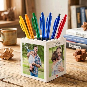 Könnte beinhalten: Ein weißer Stifthalter mit einem Foto von Vater und Kind und dem Text "I Love Dad". Der Stifthalter ist mit bunten Stiften in Gelb, Orange, Grün, Blau und Rot gefüllt. Der Stifthalter besteht aus weißen Blöcken.